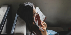Ragazza sdraiata che legge un libro con la copertina rossa per indicare i libri che cambiano la vita